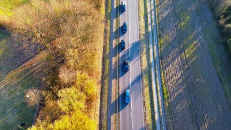 bird's-eye view of vehicles on a country road casting long shadows at dusk