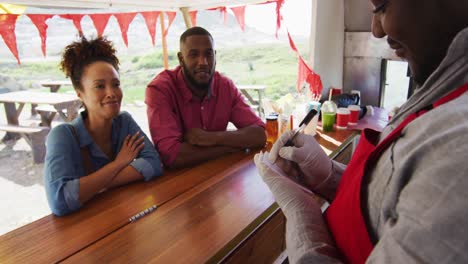 African-american-man-wearing-apron-taking-order-from-a-couple-at-the-food-truck