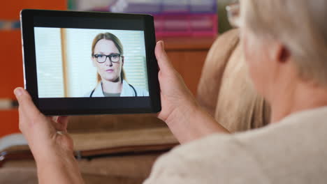 Ältere-Erwachsene-Frau-Konsultiert-Hausarzt-über-Videolink-Hält-Tablet