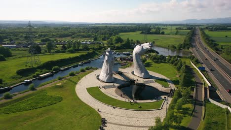 ángulo-Aéreo-Volando-Hacia-Los-Kelpies,-Un-Famoso-Monumento-Escocés-En-Falkirk-En-Un-Día-Nublado-De-Verano