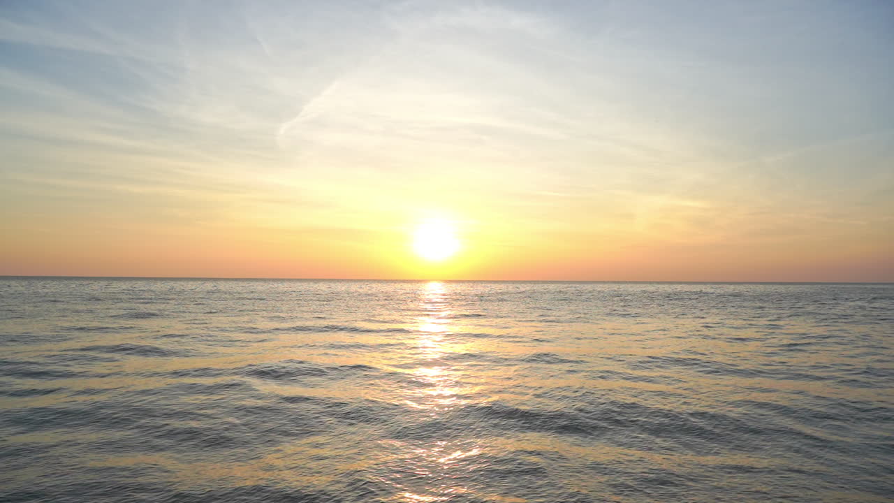 수평선 근처에 태양이 있는 바다 위로 아름다운 일몰, 움직이는 파도에 햇빛 반사