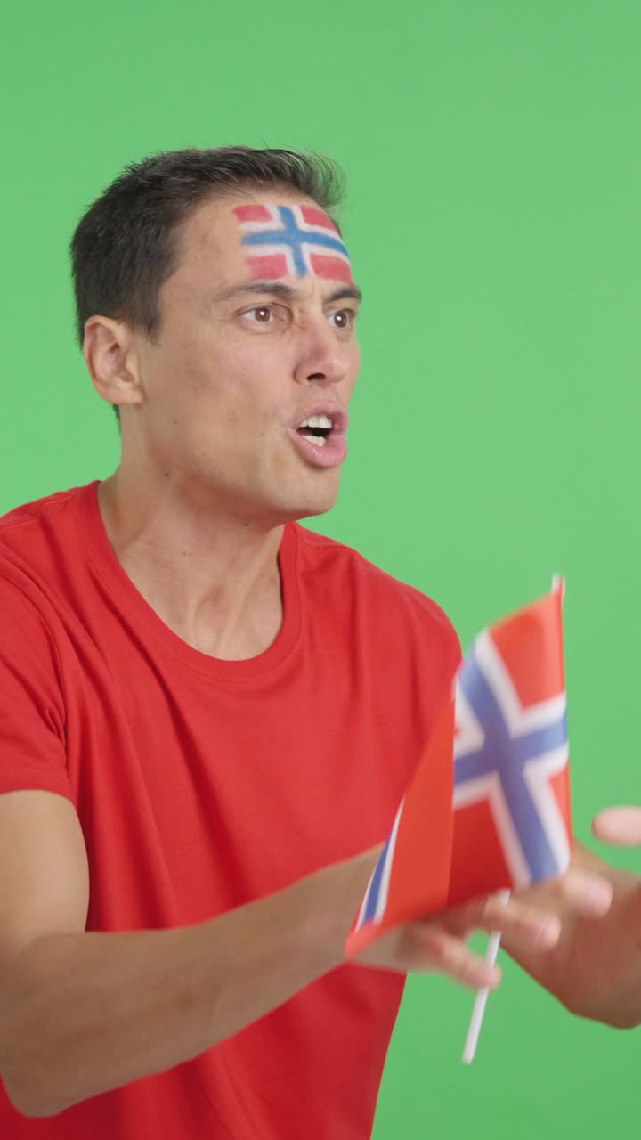Man cheering for Norway waving a national flag looking away