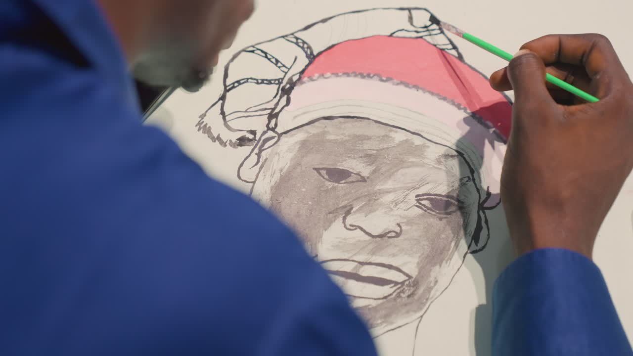 Artista ritrattista nero/a che dipinge il ritratto di un anziano, primo piano delle mani che aggiungono dettagli al cappello rosa con un pennello verde, manica blu visibile, schizzo a matita e velatura ad acquerello che costruiscono un viso texturizzato, gesti fermi.