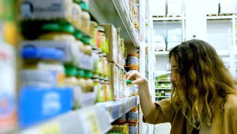 una mujer joven con una tableta compra comida para bebés en un supermercado, la niña estudia cuidadosamente la composición
