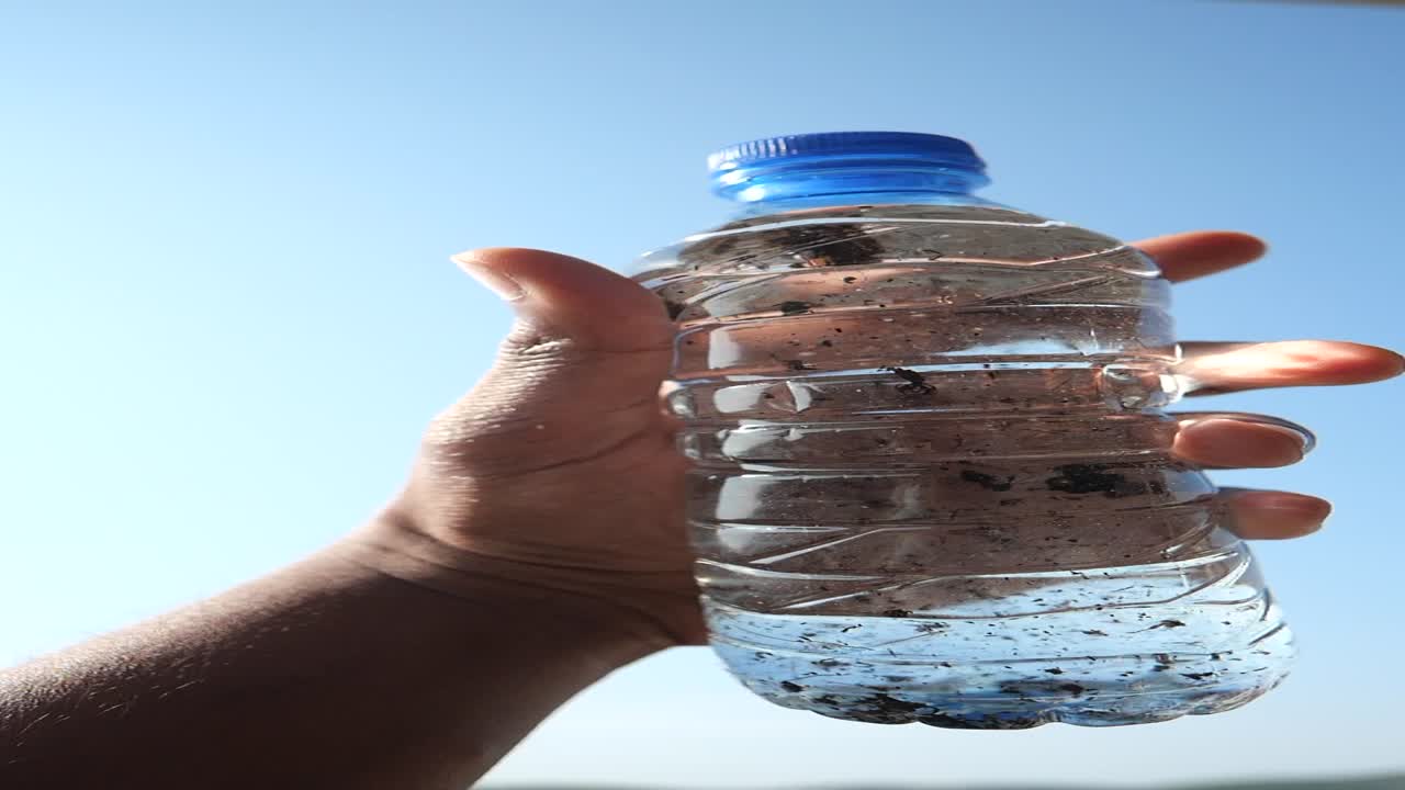 푸른 하늘을 향해 물 병을 들고 있는 손