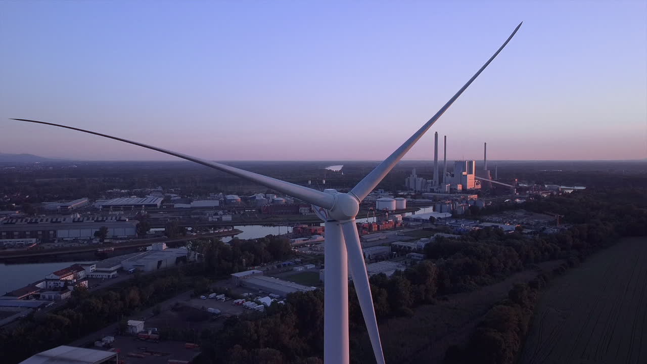 Drone footage of a wind turbine at sundown while flying over the rotor a coal energy plant comes into view symbolizing the new and the old energy supply in Europe