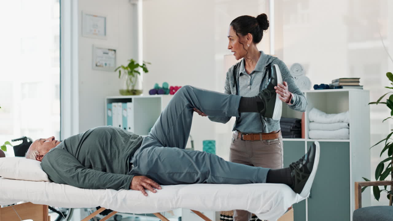 물리 치료사는 노인 환자에게 다리 운동을 도와줍니다.