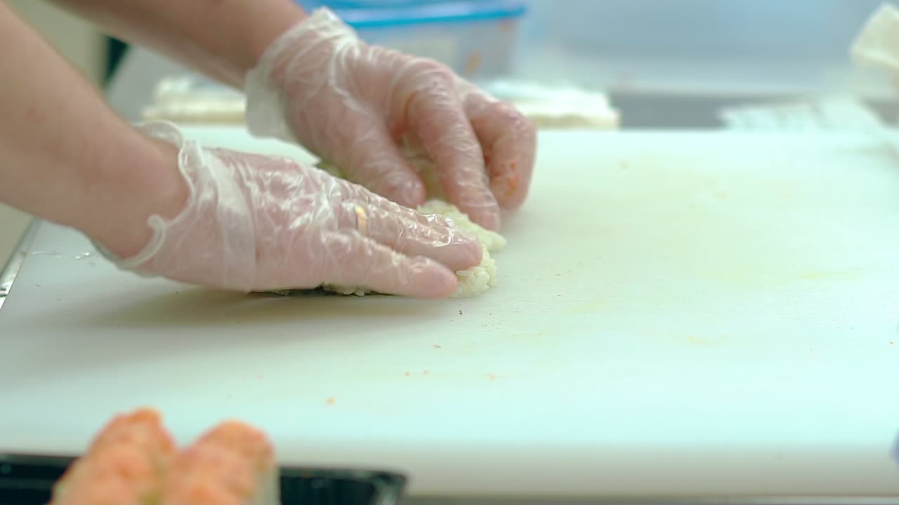el cocinero pone una capa de arroz sobre las algas nori prepara el rollo japonés