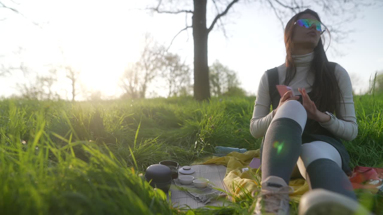 Woman enjoying a peaceful picnic in a park at sunset