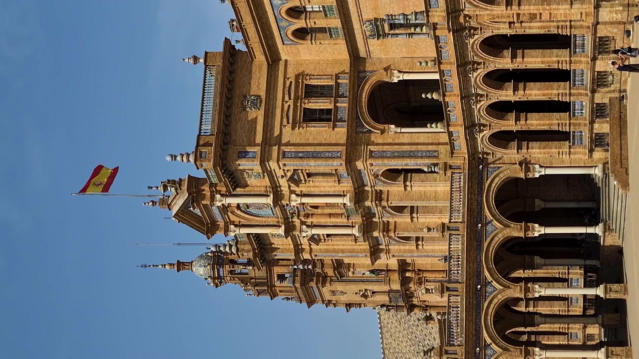 Vídeo Vertical, Bandeira Espanhola Tremulando em Edifício na Plaza de España, Sevilha. Famosa Atração Turística