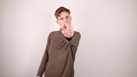 a young man spotting the camera, looks, points to it and shakes his head