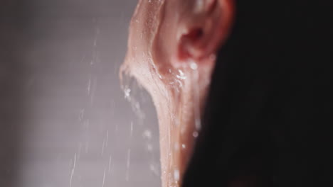 woman holds face under running water in shower closeup. pleasured lady enjoys warmth of pure sprays in home bathroom. recreation after hard day