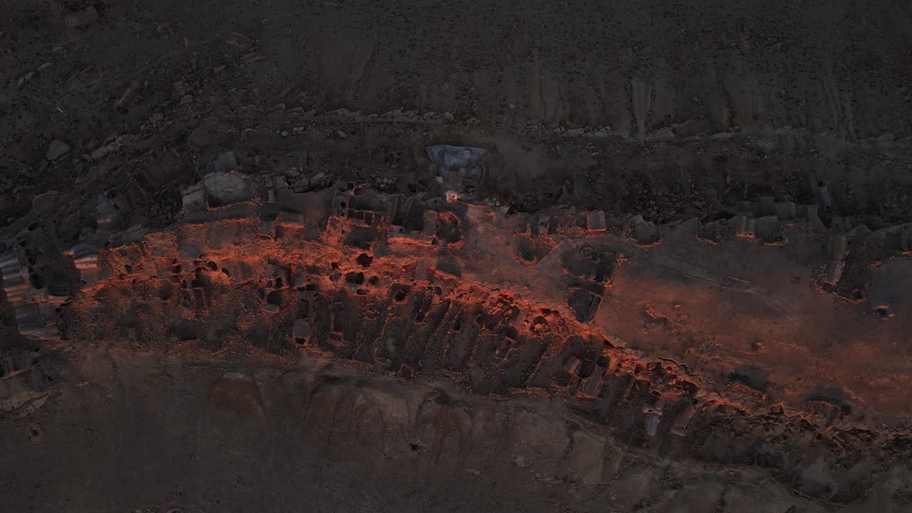Aerial view of the ancient Ksar Jarrat ruins in Tunisia at sunset. The warm light illuminates the aged stone structures.