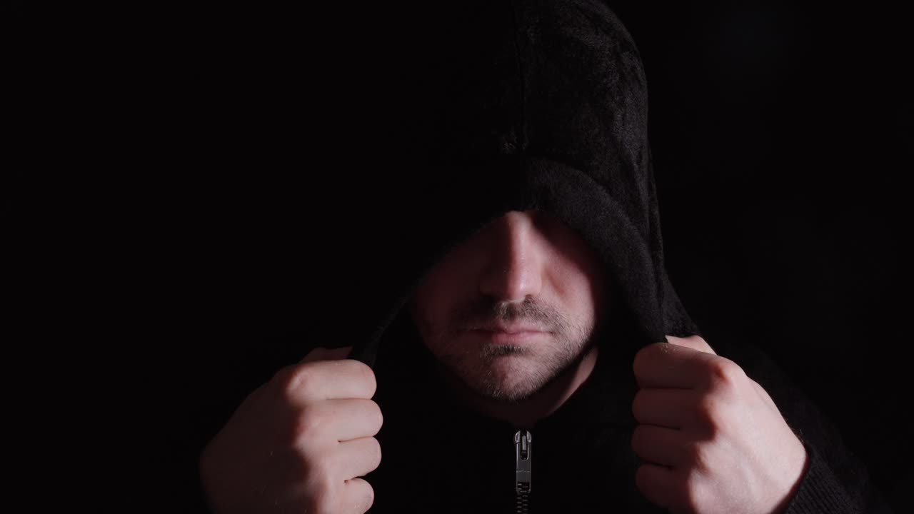 Uomo che si abbassa il cappuccio, simboleggiando identità, auto-riflessione e lotta interiore.