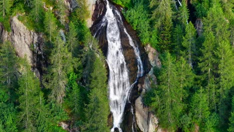 Maravillosa-Vista-Aérea-De-La-Cascada-En-La-Pared-Montañosa-Rodeada-De-árboles