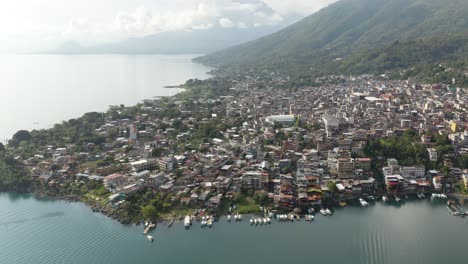 drone push in above beatiful coastline community by lake atitlan guatemala