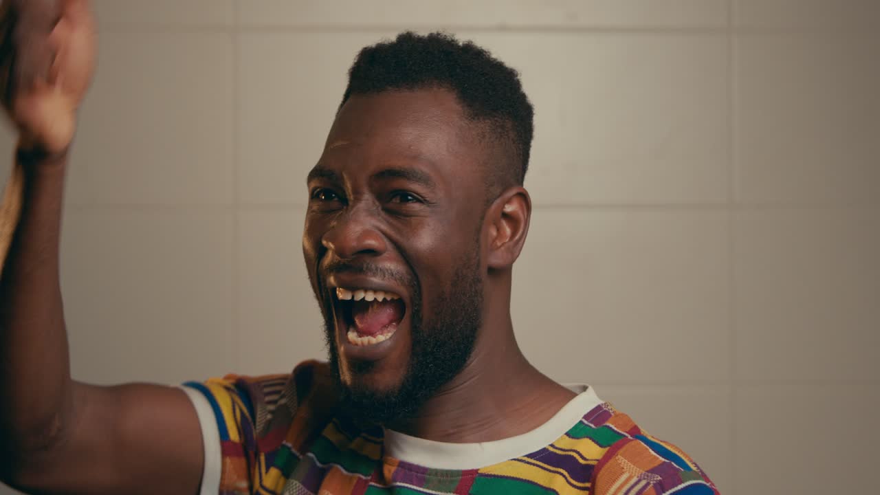 Ritratto di giovane uomo afroamericano che celebra e applaude con gioia.
