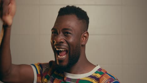 portrait of young afro american man joyfully celebrating and clapping