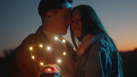 couple holding a lights heart before wedding day