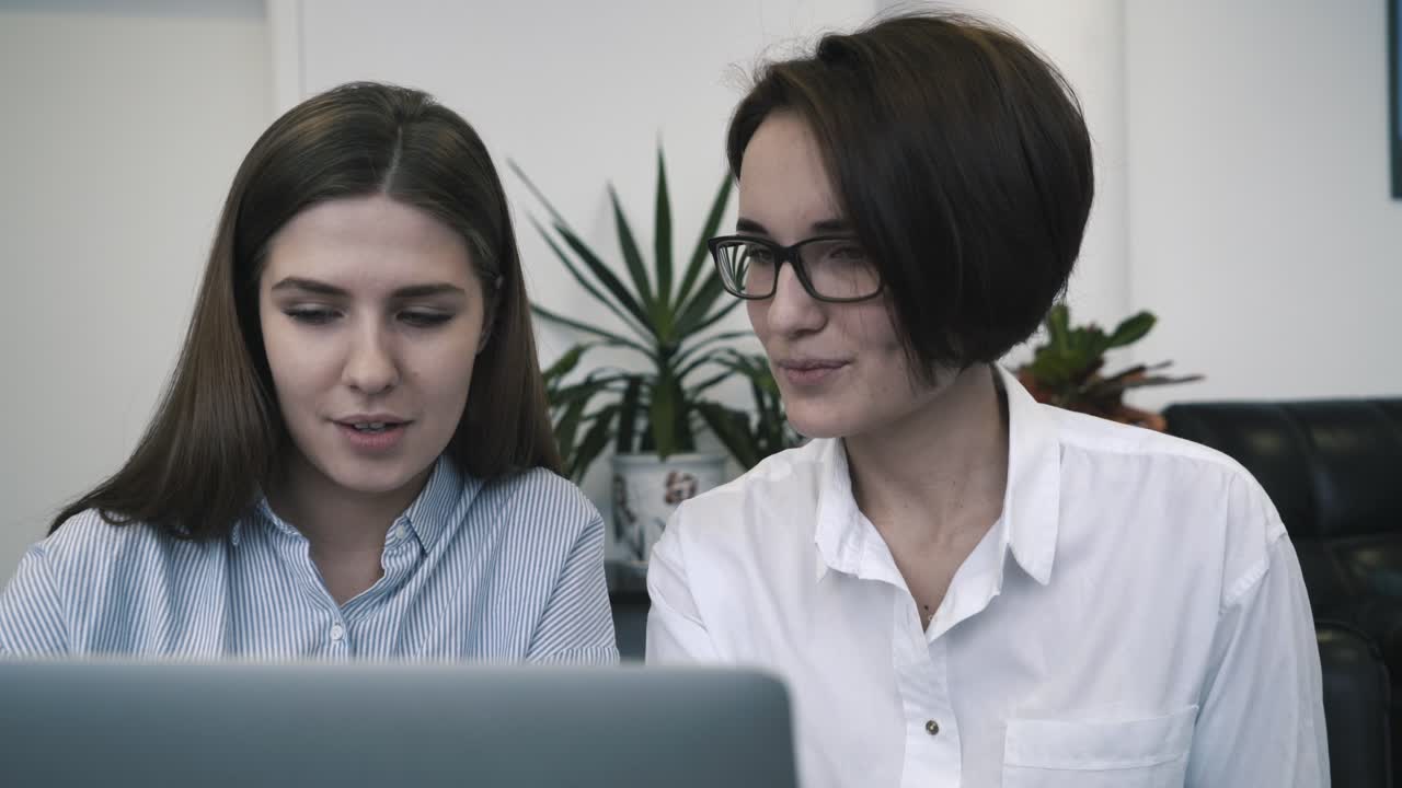 dos mujeres discutiendo el trabajo en una computadora portátil
