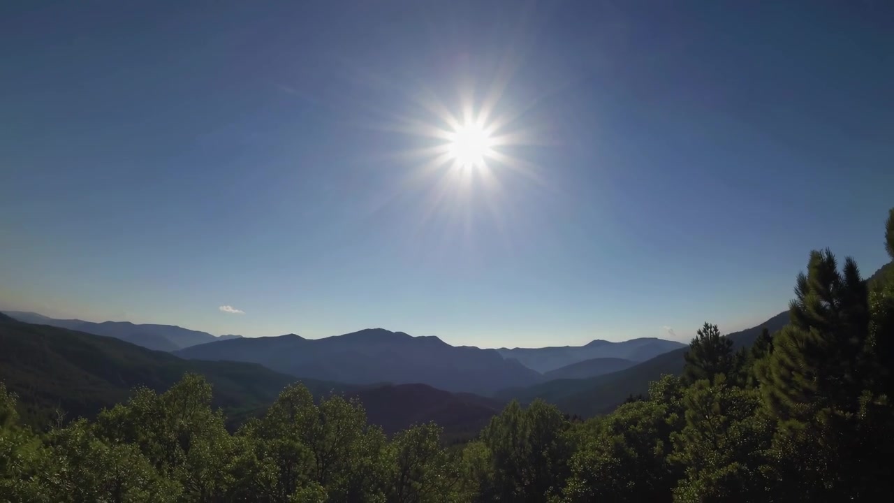 Vista aerea di una catena montuosa illuminata dal sole e di una pineta