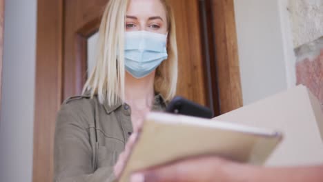 woman wearing face mask making payment to delivery man through her phone