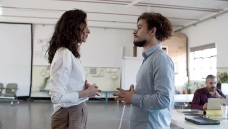 side view of focused woman talking with confident colleague in eyeglasses