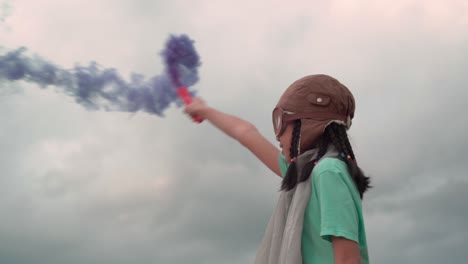 young girl with pilot goggles and hat, asian kid playing at outdoor with color smoke