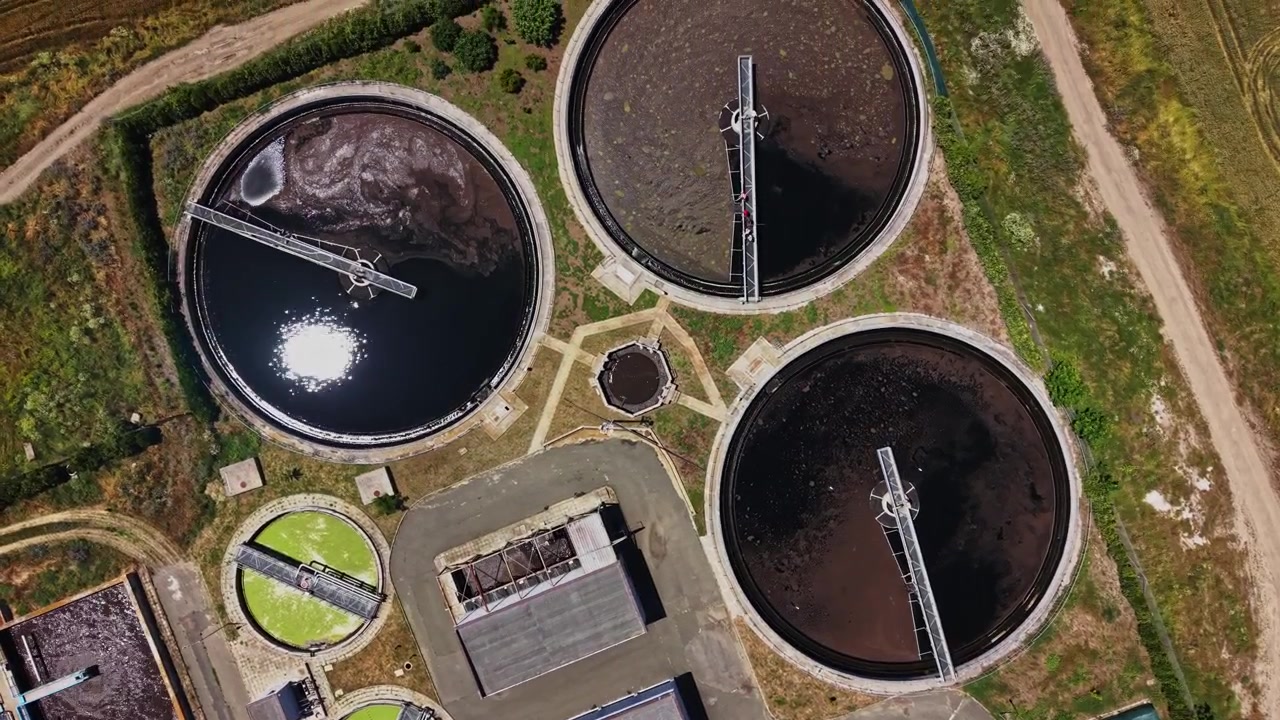 Wastewater treatment facility shows tanks and surrounding area in daylight