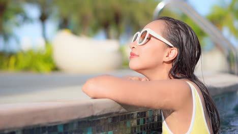 Retrato-De-Una-Mujer-Viajera-Asiática-Apoyada-En-El-Borde-De-La-Piscina-Mientras-Está-En-El-Agua