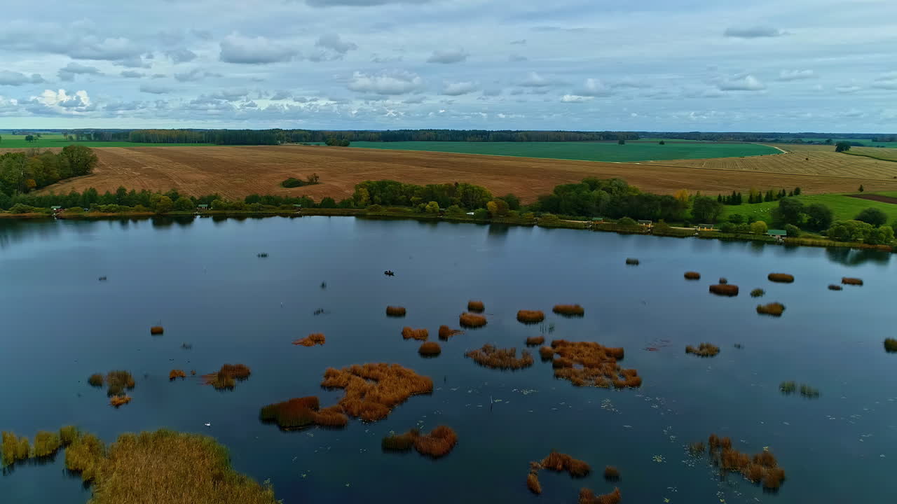 Countryside lake with small islands, aerial drone side fly view