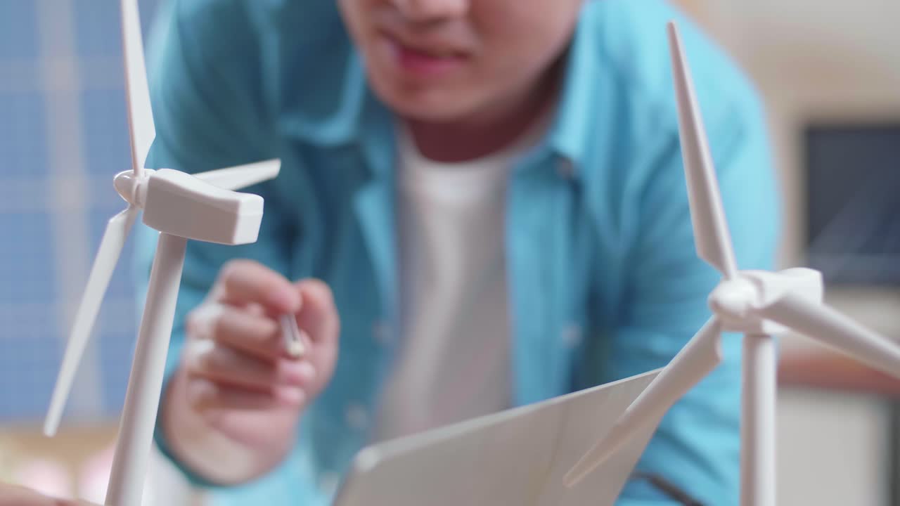 아시아 남녀가 풍력 터빈과 노트북 컴퓨터로 작업에 대해 논의합니다.