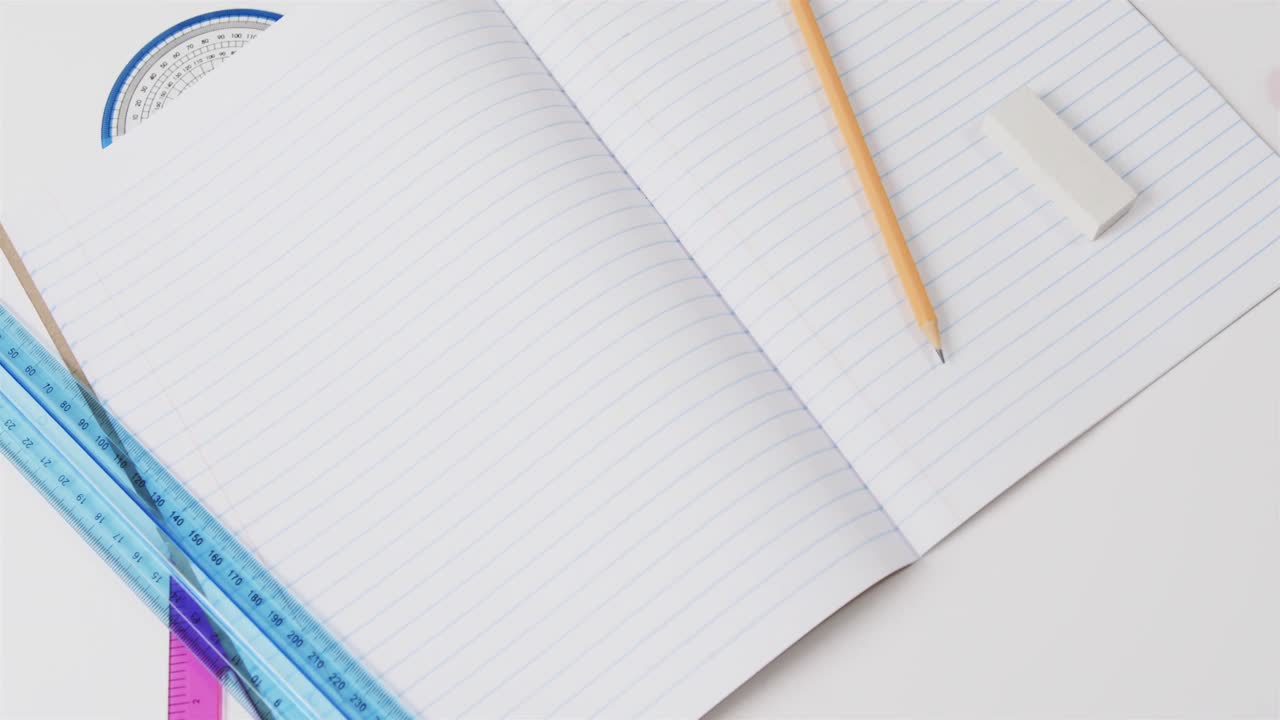 Close up of open notebook with school stationery on grey background, in slow motion