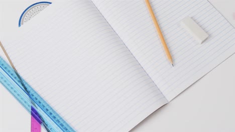 close up of open notebook with school stationery on grey background, in slow motion