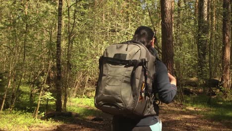 Hiking-woman-walk-with-a-hiking-backpack-in-spring-green-forest