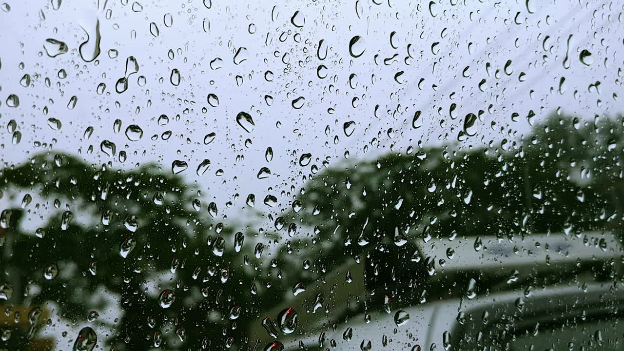 Closeup focus of water droplets on a car window during heavy rainfall