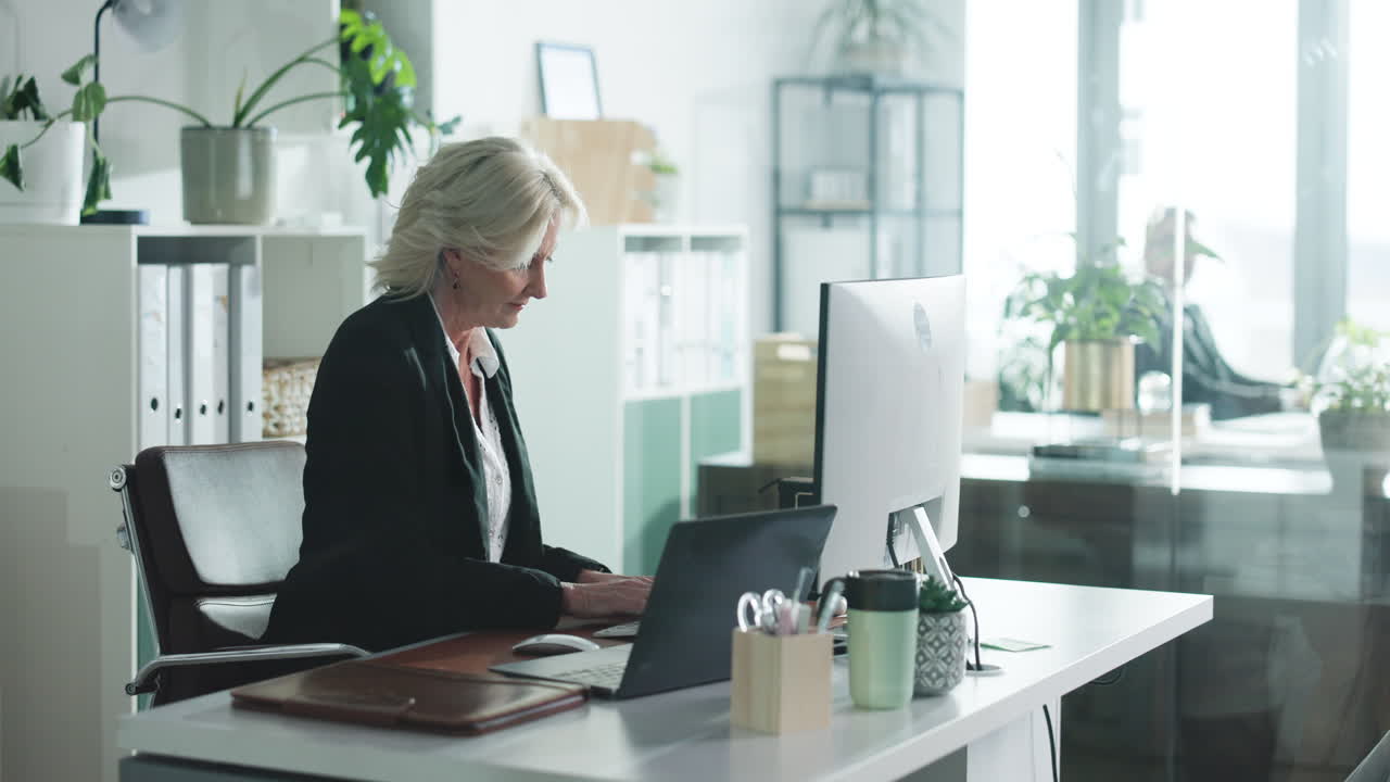 Moden kvinde, der arbejder ved sit skrivebord på et kontor