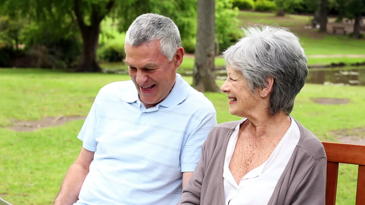 노트북 을 사용 하고 공원 벤치 에 앉아 있는 은퇴 한 부부