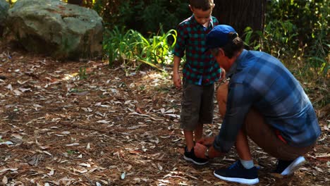 Father-helping-son-to-tie-his-shoe-lace-in-the-park