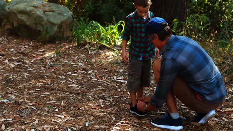 padre ayudando a su hijo a atar el cordón de sus zapatos en el parque