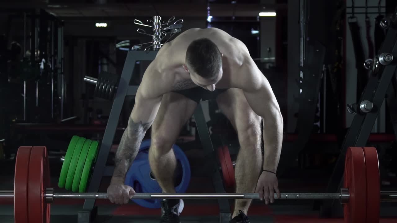 мужчина поднимает тяжести в тренажерном зале