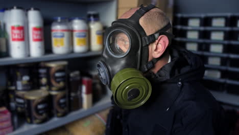 Doomsday-Prepper,-Der-In-Einem-Fallout-Bunker-Sitzt,-Eine-Gasmaske-Trägt-Und-Eine-Maschinenpistole-In-Der-Hand-Hält