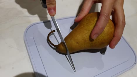 person slicing a pear on a cutting board