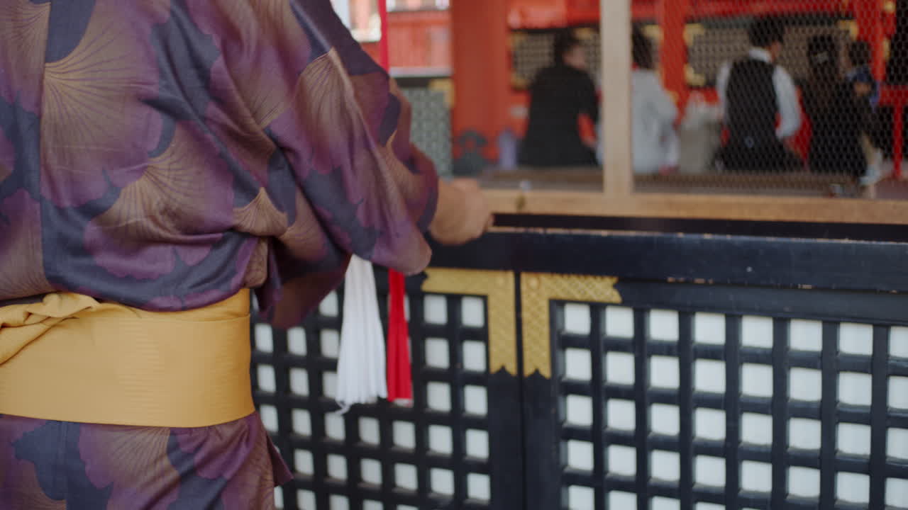Guy in yukata praying and shaking the bell at a temple in Kyoto, Japan soft lighting