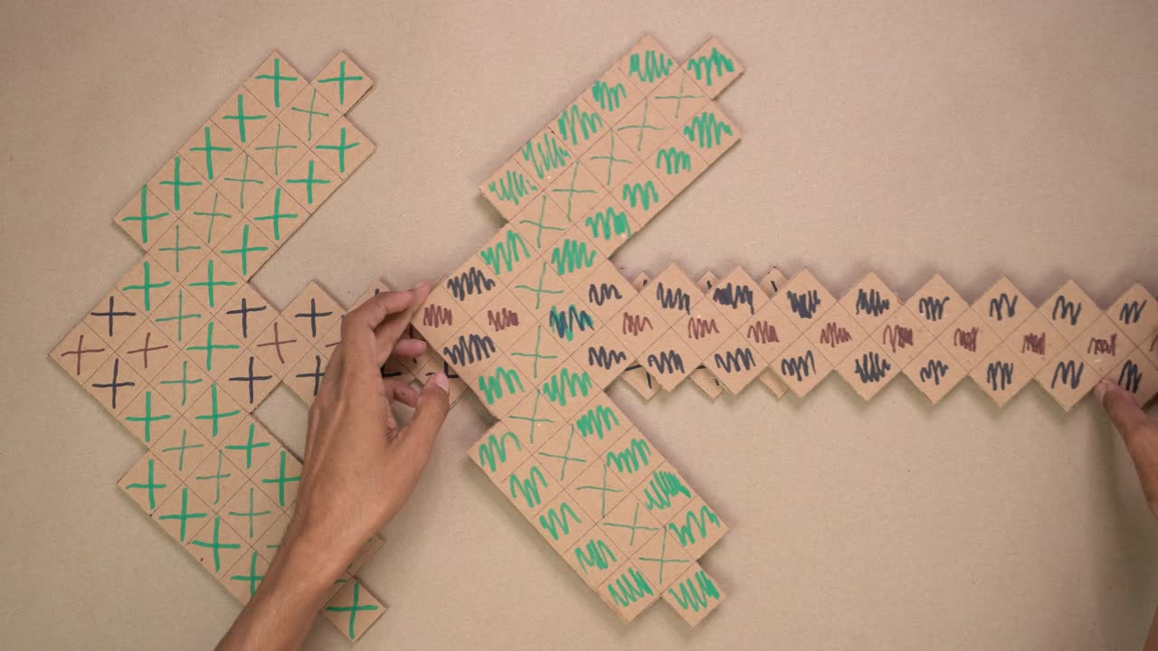 Overhead video of hands assembling and decorating pixel-style cardboard pickaxe for DIY craft activity