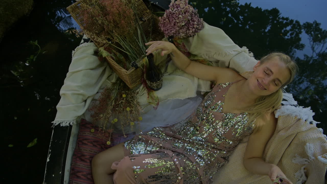 A Woman In Glittery Dress Relaxing On The Floating Boat With Flowers - overhead shot