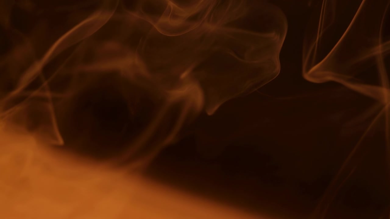 Fiamme arancioni astratte e volute di fumo si innalzano su uno sfondo scuro, formando una texture luminosa e drammatica con luce calda, movimento fluido e forte contrasto