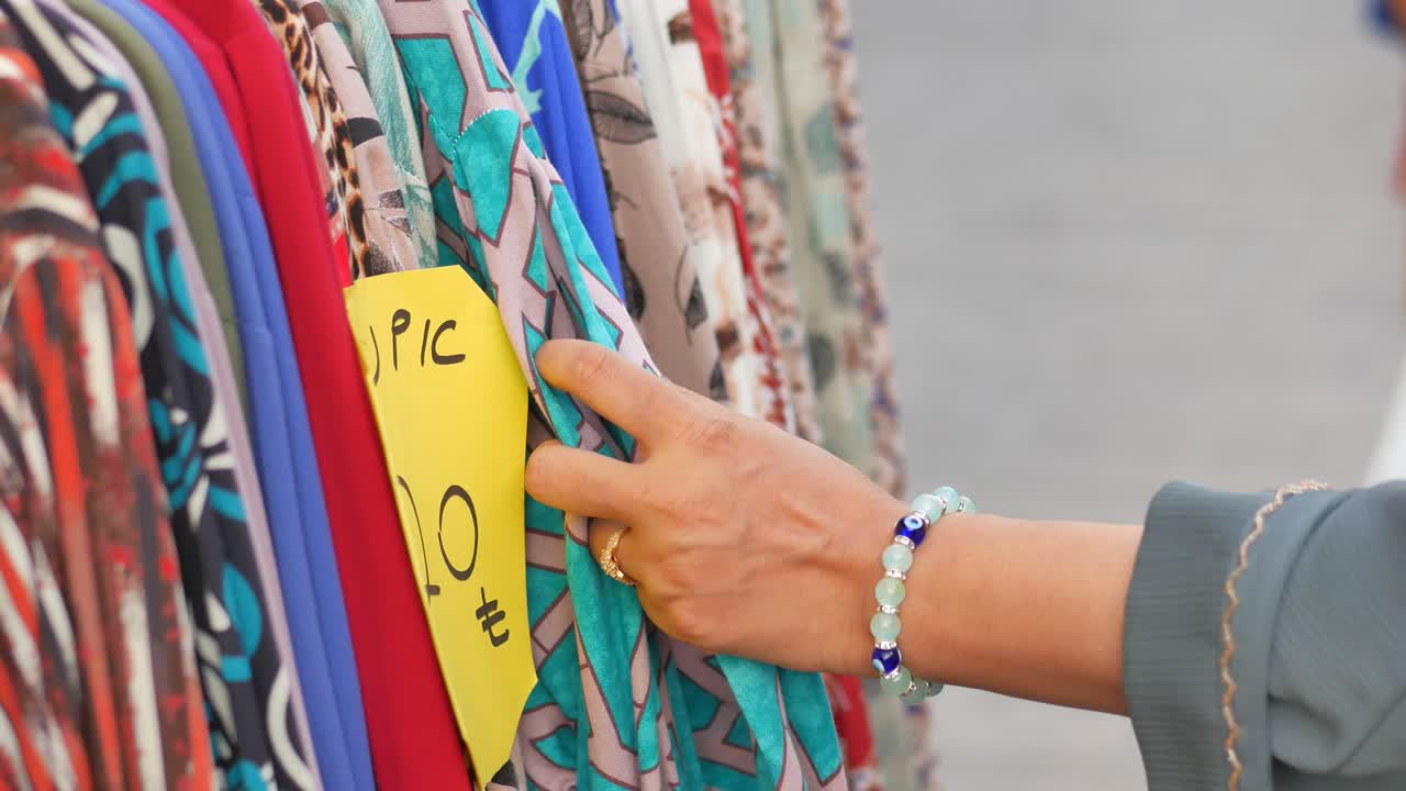 mujer comprando ropa en un mercado callejero
