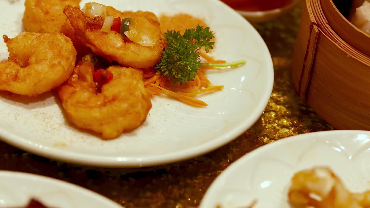 A vibrant spread of dimsum and deep-fried snacks in a Chinese restaurant setting, showcasing shrimp, vegetables, and sauces
