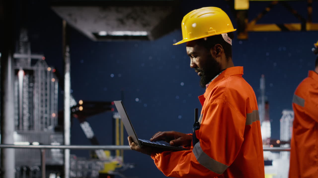 Black male engineer on offshore platform does drilling management via laptop
